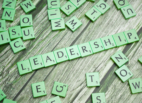 Green Scrabble-style letter tiles arranged on a wooden surface spell “LEADERSHIP,” surrounded by scattered letters, symbolizing evolving ideas and strategic thinking for leadership trends in 2026.