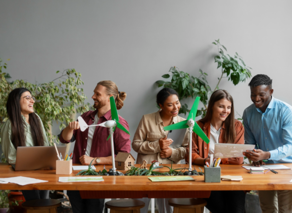 Diverse team collaborating on sustainable innovation project with green wind turbine models, representing strategic talent acquisition and high-performing workforce development.